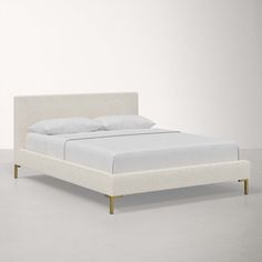 a bed with white sheets and pillows on it