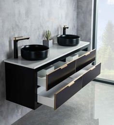 two black sinks sitting on top of a white counter next to a large glass window