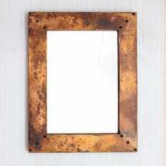 an old rusty metal frame hanging on the wall with a white blank space in the middle