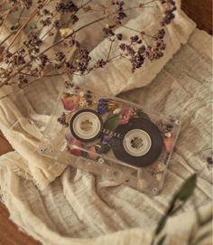 two cd's sitting on top of a table next to dried flowers and cloth