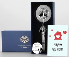 an open box with a card inside and a keychain in the front that says happy new home