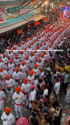 a large group of people in white and orange outfits are marching down the street together