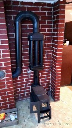 an old fashioned wood stove in front of a brick wall with pipes coming out of it