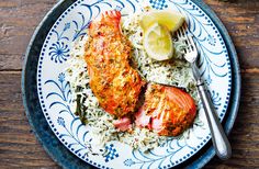 two pieces of meat and rice on a blue and white plate with a lemon wedge