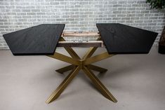 two black and gold tables sitting next to each other in front of a brick wall