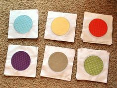 four pieces of cloth with different colored circles on them sitting on the floor next to each other