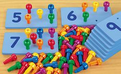 a pile of colorful plastic pegs sitting on top of a wooden table next to numbers and magnets