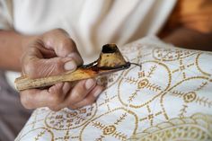 a person holding a pipe in their left hand while sitting on a couch with a decorative pillow