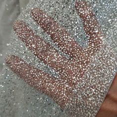 a person's hand is covered with silver sequins on a piece of cloth