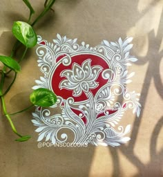 a red and white sticker sitting on top of a piece of paper next to some green plants