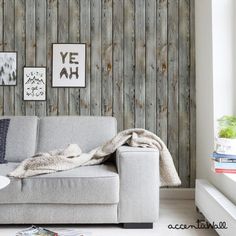 a living room with wood paneled walls and a gray couch in front of it