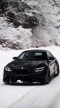 a black car driving down a snow covered road