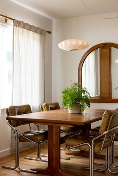 a dining room table with chairs and a mirror