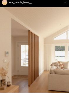 a living room filled with furniture and windows next to a wooden floor covered in white curtains