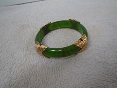 Here we have a Vintage Napier Plastic Dark Green Faux Gold Bangle Bracelet, Bangle Bracelet, Napier, Napier Forest Green Bangle, Fall Green Gold Bangle.  This is a nice Bracelet and it is marked on the backside of each gold piece with Napier, so small I do not think my camera would have shown it...  The Bracelet is in good condition and somewhat different with the gold on it as well and it is 2 1/2 inches wide on the inside of the circle and it is 1/2 of an inch tall and will look great this fal Adjustable Green Costume Jewelry Bracelets, Elegant Green Stretch Bangle Bracelet, Elegant Green Bangle Stretch Bracelet, Fall Green, Gold Piece, Gold Bangle Bracelet, Gold Bangle, Bracelet Bangle, Green Gold