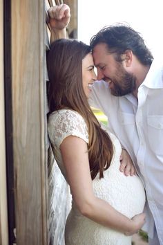 a pregnant woman standing next to a man