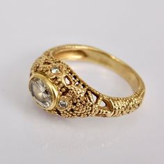 a gold ring with an oval stone surrounded by filigrees and small stones