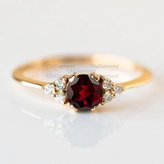 a gold ring with a red stone and two white diamonds