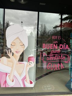 there is a woman holding a cup in front of a store window that has been painted on