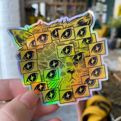 a person holding up a sticker with cats'eyes on it in front of a yellow couch