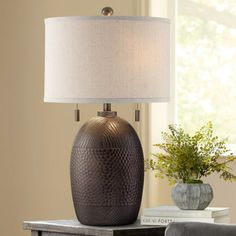 a table lamp sitting on top of a wooden table next to a vase with flowers