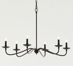 a black chandelier with six lit candles hanging from it's center point