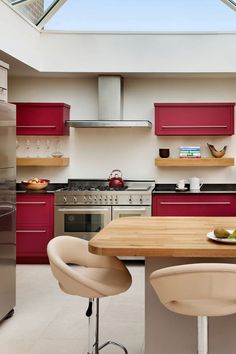 a modern kitchen with red cabinets and stainless steel appliances