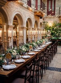 a long table is set up with white flowers and greenery for an elegant wedding reception