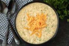 a black bowl filled with cheese on top of a table next to utensils