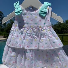 New Mayoral Sweet White Cotton Dress With Eyelet Circles Shaded In Pink, Aqua, And Yellow Thread. Bows Over The Shoulder And Zips Up. This Is Mayoral's Infant Line And The Sizing Is European. They Do More Size Ranges Than We Do Here In The Us. It Goes Like This 0-1m=Newborn, 1-2m= 0-3m 2-4m= 3m, 4-6m=6m, 6-9m= 9m, And Then 12m. I Am Listing In The Us Sizes. All Of My Items Come From My Children's Boutique. All Brand New And Directly From The Manufacturer. Please Feel Free To Ask Any Questions. Fun White Summer Dresses, White Floral Print Dress For Playdate, White Sleeveless Sweet Dress, Sweet White Sleeveless Dress, Fun White Beach Dress, Cute White Cotton Dress, Playful White Spring Dresses, White Dress For Spring Playdate, Multicolor Ruffle Dress For Playwear