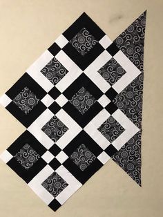 a black and white patchwork quilt on the wall with an interesting design in it