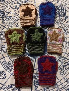 six crocheted oven mitts sitting on top of a white cloth covered table