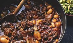 a pan filled with meat and vegetables on top of a table next to other foods