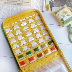 a yellow and green tray with different colored thread spools on top of it