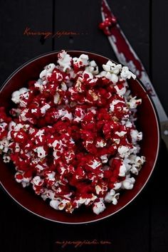 a red bowl filled with popcorn on top of a table