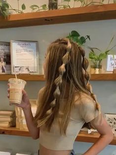 a woman standing in front of shelves holding a drink