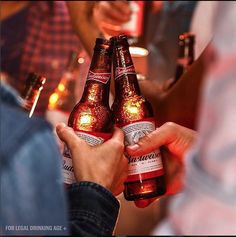 two people holding beer bottles in their hands