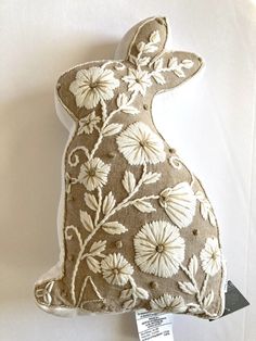 a decorative pillow with an embroidered bunny on it's back and flowers in the front