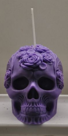 a purple skull with roses on it's head and a toothbrush in its mouth