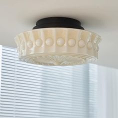 the light fixture is hanging from the ceiling in the room with blinds on the windowsill