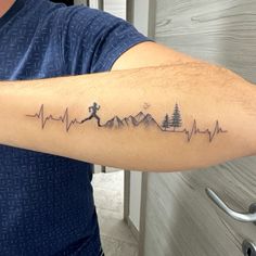 a man with a tattoo on his arm that has a heartbeat running through the mountains