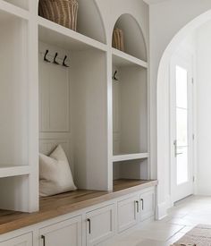 a room with some white cupboards and pillows on top of each shelf in front of the door