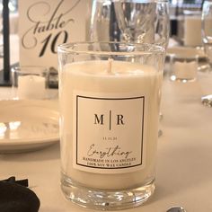 a white candle sitting on top of a table next to a plate and wine glasses