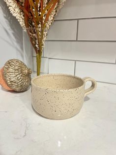 a white bowl sitting on top of a counter next to a plant