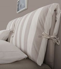 an upholstered headboard with white pillows in a gray and white bedroom setting