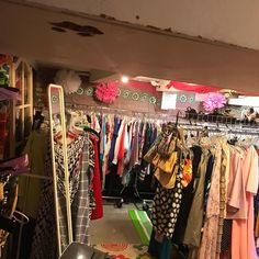 a clothing store filled with lots of clothes and handbags hanging from the ceiling,