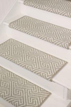 the stair treads are made from white wood and beige rugs with an intricate pattern on them