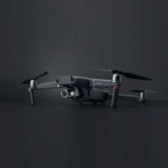 a black and silver remote control flying in the air on a dark background with no one around it