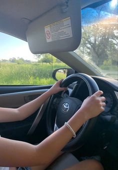 a woman driving a car with her hand on the steering wheel