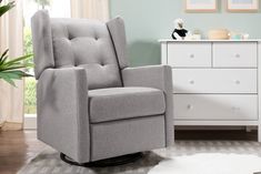 a gray recliner chair sitting on top of a rug in front of a white dresser